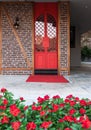 Bright red iron doors surrounded by red flowers on a brick wall Royalty Free Stock Photo