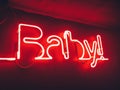 Bright red neon baby sign, indoor glowing light in bar. Night club party lights.