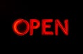 Bright red neon letters OPEN flash on a black background