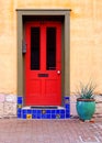 Brightl red, painted door with tile trim, on a yellow stucco building Royalty Free Stock Photo