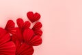 Bright red paper hearts of asian ribbed fans soar as flow on pastel pink background, top view, copy space. Festive wedding love.