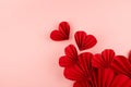 Bright red paper hearts of asian ribbed fans soar as flow on pastel pink background, top view, copy space. Festive wedding love.