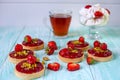 Bright red pastry tartlets, decorated with strawberries and pistachios on a blue wooden background Royalty Free Stock Photo