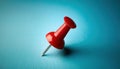 Red pushpin resting on a blue surface in a minimalist setting
