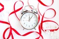 Bright red ribbon and a beautiful vintage silver alarm clock isolated on white background Royalty Free Stock Photo