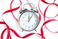 Bright red ribbon and a beautiful vintage silver alarm clock isolated on white background Royalty Free Stock Photo