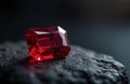 Bright red ruby gemstone rests on dark textured surface. The precious stone sparkles. Jewelry accessory or a symbol of wealth and Royalty Free Stock Photo