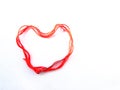 Bright red wool thick thread with a sewing needle lies in the shape of a heart isolated object on a white background Royalty Free Stock Photo