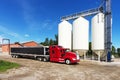 Bright Red Semi Truck by White Grain Storage Silos