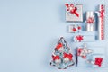 Bright red, silver and pastel blue christmas background of gift boxes and christmas tree with glitter balls with copy space.