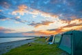 Bright red sunset over the beach, there are a number of tents. tourist camp