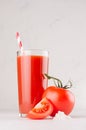 Bright red tomato cocktail in elegance glass with glossy tomatoes, salt, straw and ripe piece on white wooden board, vertical. Royalty Free Stock Photo