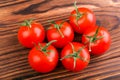 Bright red tomatoes with leaves on the wooden background. Close-up of fresh, juicy, organic, ripe, useful and bright red tomatoes. Royalty Free Stock Photo