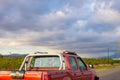 Bright red truck driving by. Beautiful cloudy sky and grassy field in background. Royalty Free Stock Photo