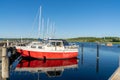 Bright red and white sailboat in a marina with darl blue water under a blue sky Royalty Free Stock Photo