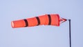 Bright red wind sock displays movement against clear blue sky, signaling wind direction at an outdoor location Royalty Free Stock Photo