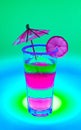 bright rich neon cocktail in a tall glass with an umbrella and a piece of fruit