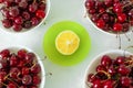 Bright ripe cherries in white plates and half a lemon Royalty Free Stock Photo