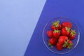 Bright ripe juicy strawberry in a transparent plate on blue background. Royalty Free Stock Photo