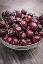 A bright ripe sweet cherry covered with cold drops of water lies in a transparent bowl Royalty Free Stock Photo