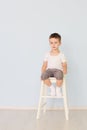 Bright room. Boy in white shirt sitting in a high chair