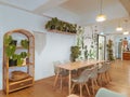 Bright room with hardwood floors and a wooden table and chairs adorned with lush green plants.