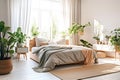 Bright room with wooden bed covered with grey bedding. Nordic interior design of modern bedroom with many green houseplants.