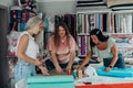 In bright sewing workshop women collaborate on a textile project using scissors threads and rulers while surrounded by Royalty Free Stock Photo