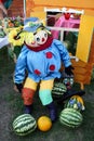 Bright sewn doll sits next to a painted house and watermelons