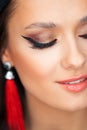 Bright sexy makeup and red tassel earrings. Portrait of a brunette girl.