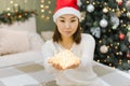 Shining lights in hands of young asian woman with santa hat, magic decoration at New Year or Christmas Royalty Free Stock Photo