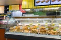 Bright shot of burgers, donuts and sandwiches in a bakery or shop glass counter.