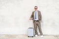 With a bright smile and a casual stance, a senior experienced businessman stands with his suitcase Royalty Free Stock Photo