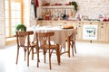 Bright spacious dining room with large wooden oval table. room with a wooden dining table, chairs and a kitchen in a modern house.