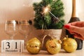 Bright sparkler against New Year festive background with champagne, christmas balls, champagne glasses, calendar dated December 31
