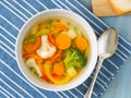 Bright spring vegetable soup with cauliflower, broccoli, pepper, carrot, green peas. Top view, blue wooden background. Royalty Free Stock Photo