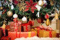 Bright studio shot of gift boxes in front of a gorgeous lush Christmas tree, decorated in red and gold.