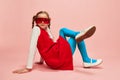 Bright style. Beautiful little girl, child in red dress, blue tights and red glasses posing over pink studio background Royalty Free Stock Photo