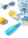 Bright summer beach vacation or travel lifestyle concept flat lay with lemonade, a sun umbrella, sunglasses and sunscreen spray. Royalty Free Stock Photo