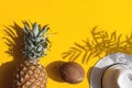 Bright summer composition. Coconut, pineapple, and hat on a yellow background with deep shadows. Summer, vacation concept. Top