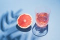 Bright summer drink concept made of crystal glass, palm tree shadow and grapefruit on blue background. Trendy minimal concept Royalty Free Stock Photo