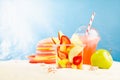 Bright summer fruit salad with sliced fruit - strawberry, mango, grapefruit, apple in plastic box with cold juice, sun hat on sun. Royalty Free Stock Photo