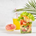 Bright summer lunch set with seafood salad with shrimps, red bell pepper, lettuce, croutons in plastic pack, fresh orange juice. Royalty Free Stock Photo