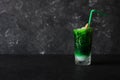 Bright, summer refreshing drink in a tall glass with crushed ice on a dark background. Top view with copy space