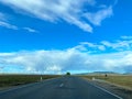 Bright summer scene with empty road, blue sky and rainbow in the distance. Beauty of nature, travel concept Royalty Free Stock Photo