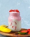 Bright summer strawberry-banana smoothie with coconut in a jar. Royalty Free Stock Photo