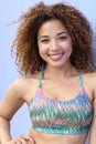 Bright summer trendy portrait of young fit Latina girl walking on the street, wearing vivid crop top, long curly afro hair