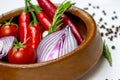 Bright summer vegetables: onion, garlic, tomato, red chili pepper, rosemary in brown wooden bowl and peppercorns Royalty Free Stock Photo