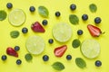 Bright summer yellow background with slices of citrus lime mint blueberry strawberry berries Flat lay Royalty Free Stock Photo