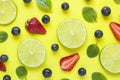 Bright summer yellow background with slices of citrus lime mint blueberry strawberry berries Flat lay Royalty Free Stock Photo